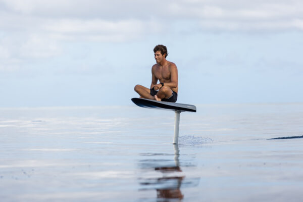 A person sitting on a Fliteboard, enjoying a thrilling water sport experience. The hydrofoil surfboard is sleek and streamlined, designed for gliding above the water's surface. The rider is positioned comfortably, ready to navigate the waves with excitement and control. The Fliteboard offers a unique and exhilarating way to explore the aquatic world.