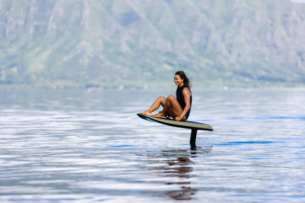 Green Fliteboard PRO gracefully skimming the surface of a serene lake, showcasing its sleek design and exhilarating performance with a touch of vibrant allure.