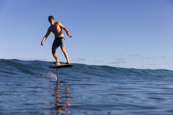 Adventurous man carving through waves on the Fliteboard ULTRA, showcasing its thrilling performance and sleek design.